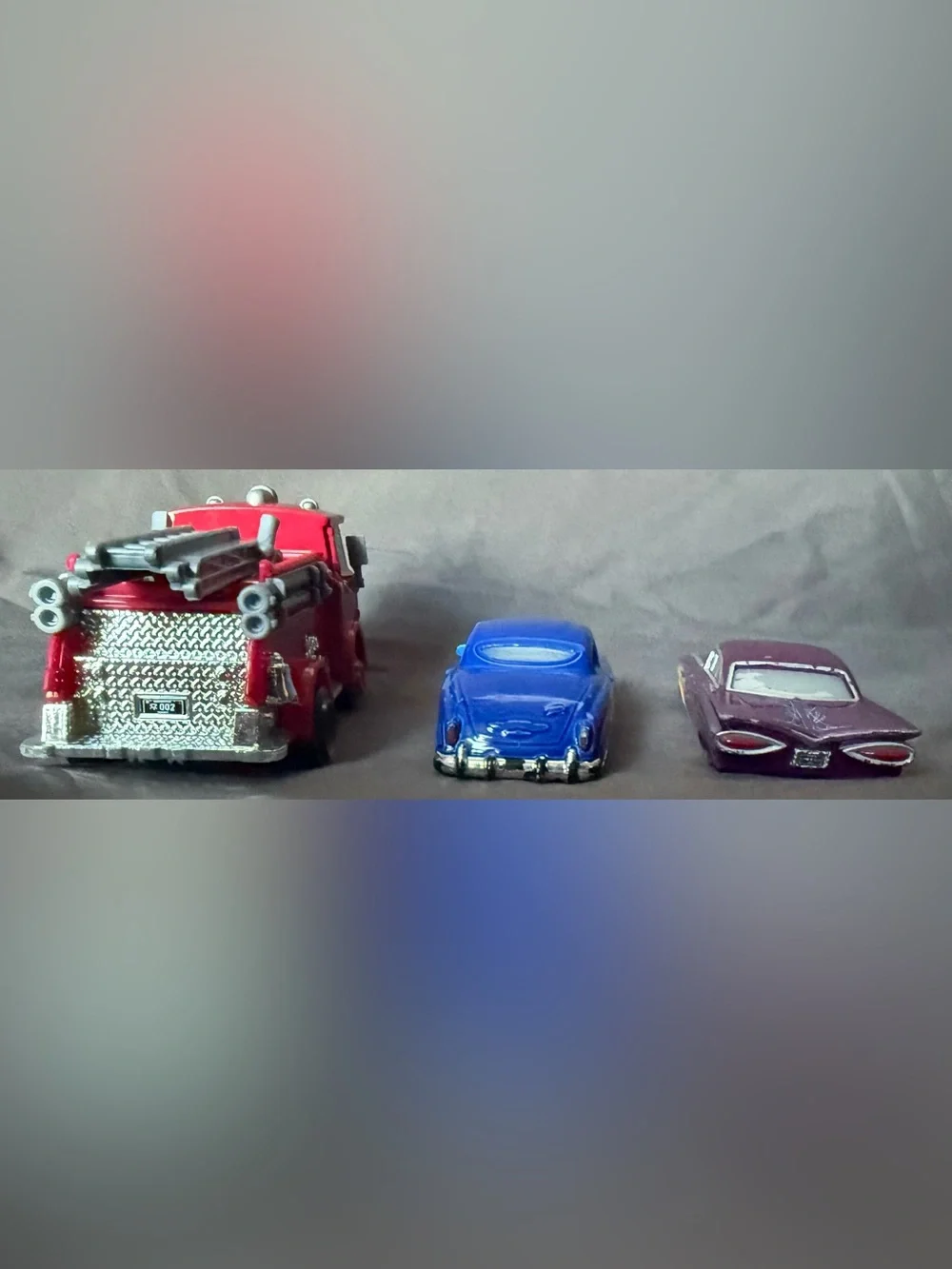 Disney Pixar Cars Diecast: Red Fire Truck, Doc Hudson, and Purple Ramon.
